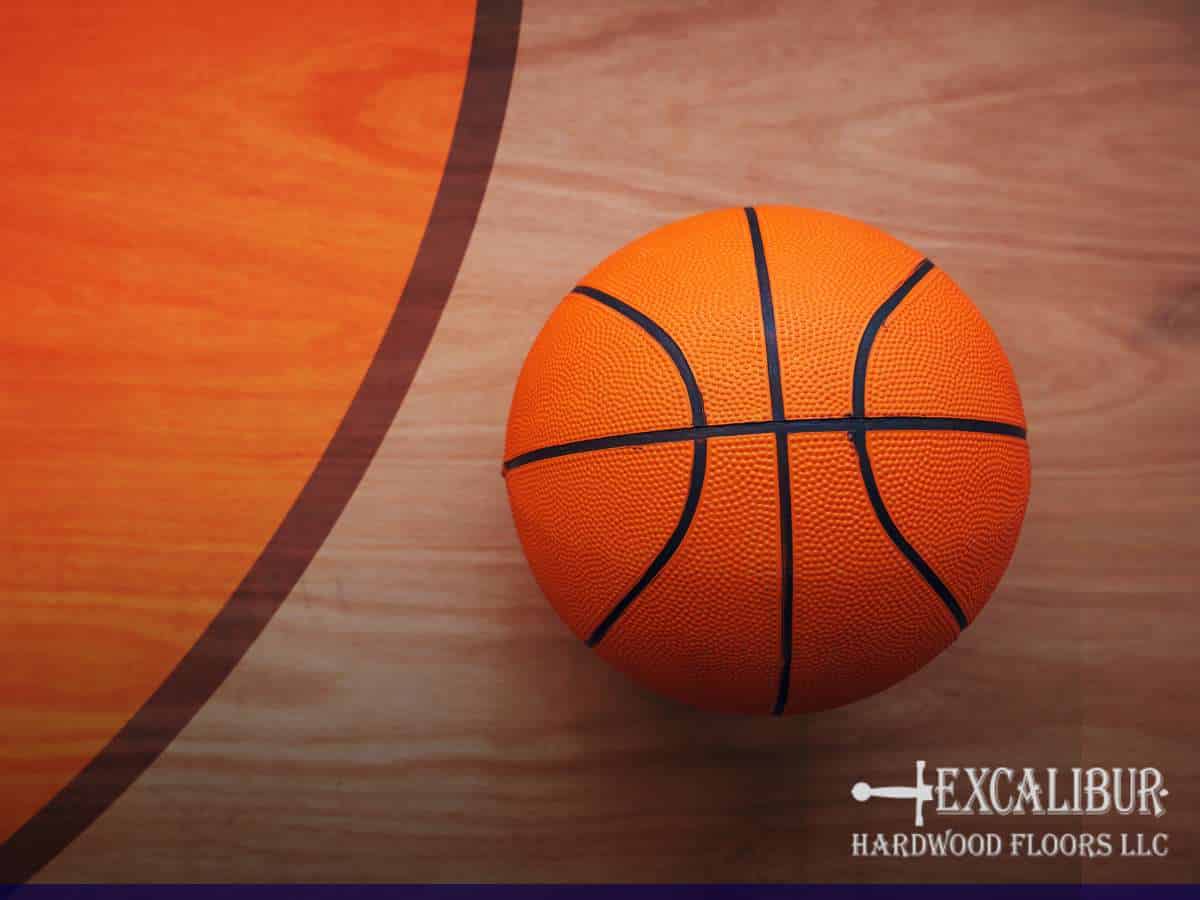 Basketball resting on a gym's hardwood floor, highlighting the need for proper maintenance and refinishing